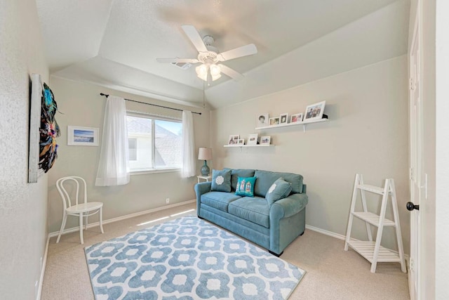 living area featuring a ceiling fan, a tray ceiling, carpet, and baseboards