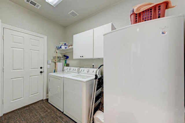 laundry room with dark wood finished floors, visible vents, cabinet space, and washer and clothes dryer