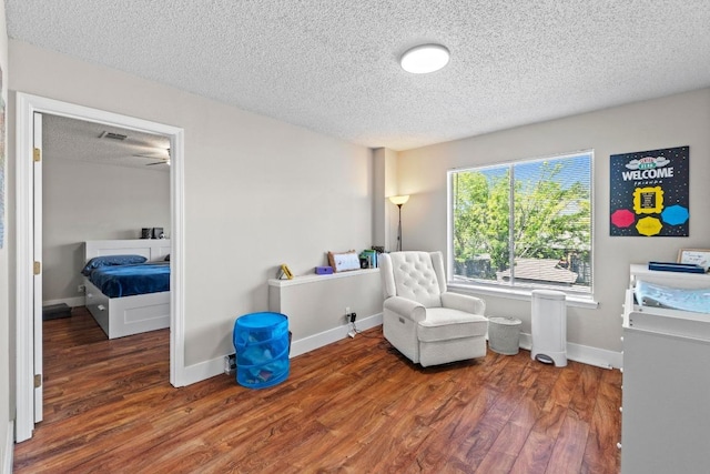 living area with baseboards, wood finished floors, and a textured ceiling
