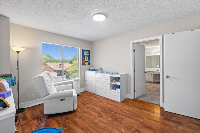 sitting room with a textured ceiling, wood finished floors, and baseboards
