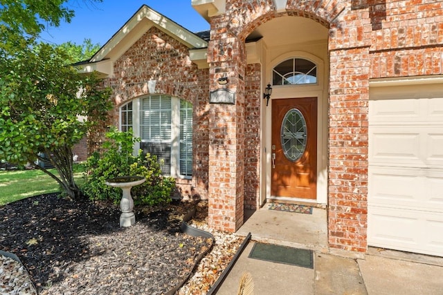 entrance to property with an attached garage and brick siding