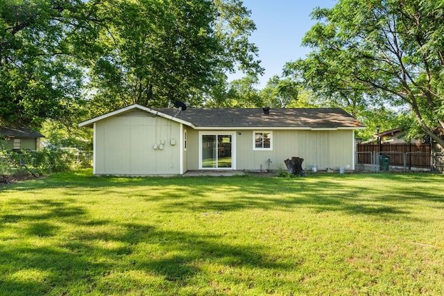 rear view of house with fence and a lawn