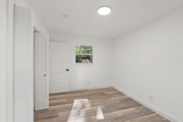 unfurnished room with baseboards and light wood-type flooring