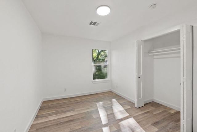 unfurnished bedroom with visible vents, light wood-style flooring, and baseboards
