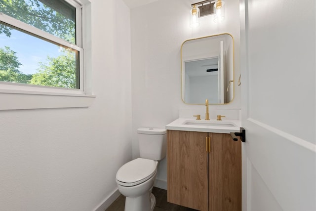 bathroom featuring toilet, vanity, and baseboards