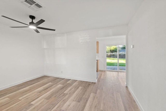 spare room featuring a ceiling fan, visible vents, light wood-style flooring, and baseboards
