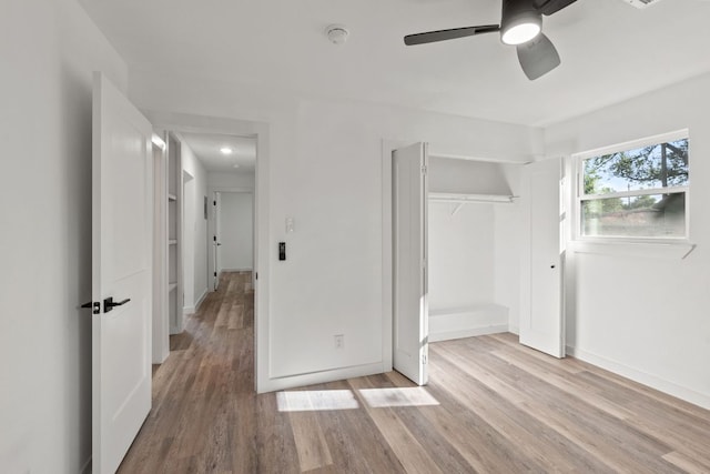 unfurnished bedroom featuring baseboards, ceiling fan, light wood-style floors, and a closet