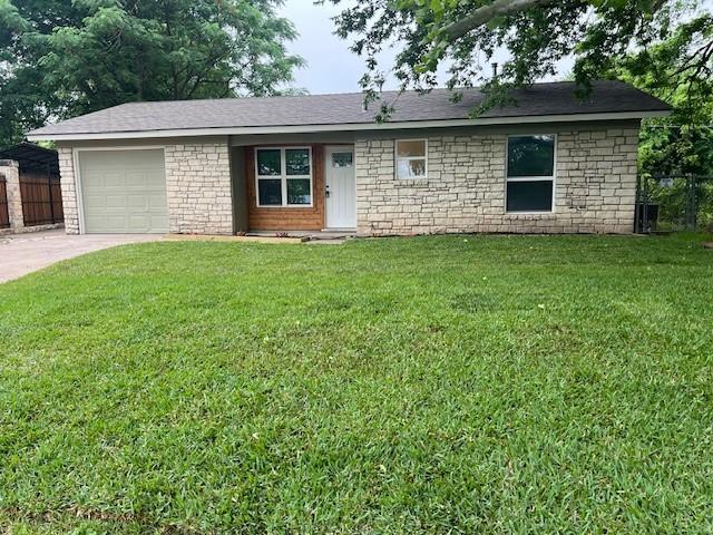 ranch-style house with a front lawn, concrete driveway, an attached garage, and stone siding