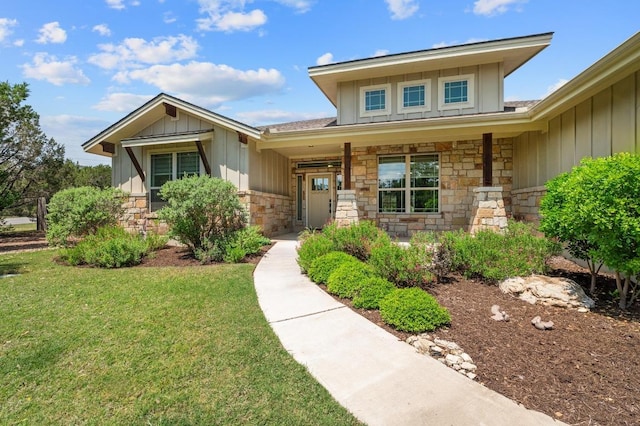 view of front of property featuring a porch, a front lawn, stone siding, and board and batten siding