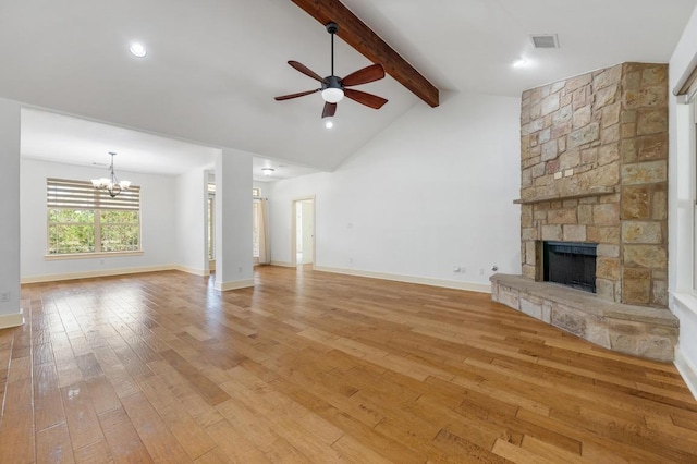unfurnished living room with lofted ceiling with beams, light wood-style floors, ceiling fan with notable chandelier, a stone fireplace, and visible vents