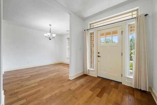 entrance foyer with baseboards, light wood-type flooring, and a notable chandelier