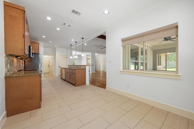 kitchen with tasteful backsplash, visible vents, a sink, and brown cabinets