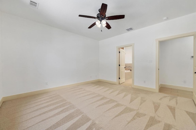 unfurnished bedroom with light colored carpet, visible vents, ensuite bath, and baseboards