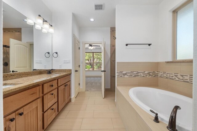full bathroom with a sink, a bath, ceiling fan, double vanity, and visible vents