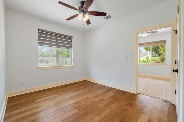 unfurnished room featuring visible vents, ceiling fan, light wood-style floors, and plenty of natural light