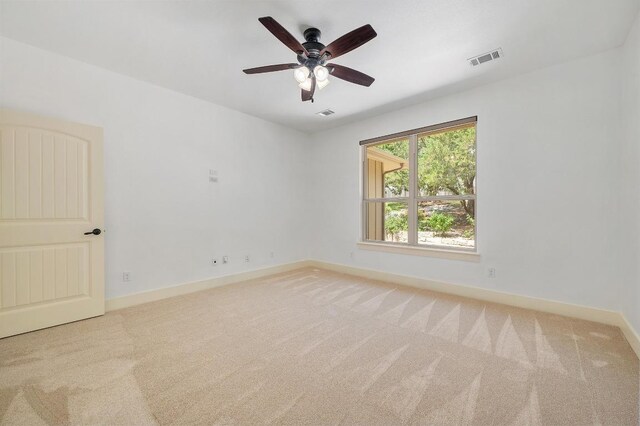 unfurnished room with a ceiling fan, visible vents, light carpet, and baseboards