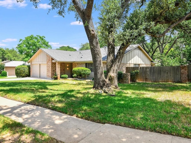 view of front facade with board and batten siding, an attached garage, fence, brick siding, and a front lawn