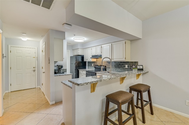 3404 American Dr Unit 3208, Lago Vista, TX 78645 - kitchen featuring black appliances, under cabinet range hood, a peninsula, light tile patterned floors, and light stone counters