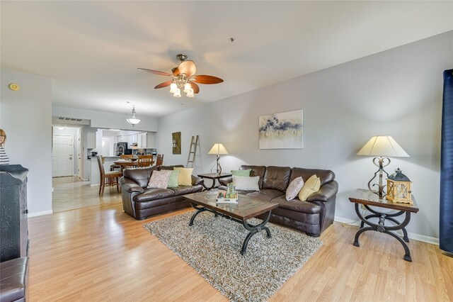 living area with ceiling fan, light wood-style flooring, and baseboards