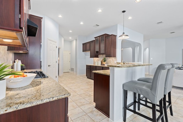 2129 Aaron Ross Way, Round Rock, TX 78665 - kitchen featuring backsplash, a peninsula, a breakfast bar, light stone countertops, and recessed lighting