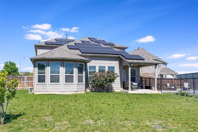 back of house featuring a lawn, a fenced backyard, solar panels, and a patio area