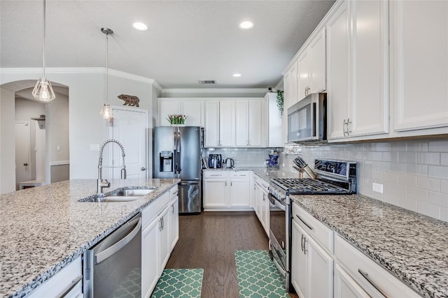 kitchen featuring arched walkways, appliances with stainless steel finishes, ornamental molding, a sink, and visible vents