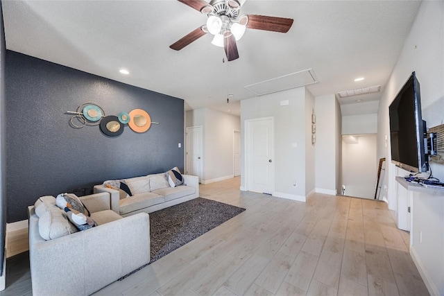 living area with attic access, recessed lighting, ceiling fan, light wood-type flooring, and an accent wall