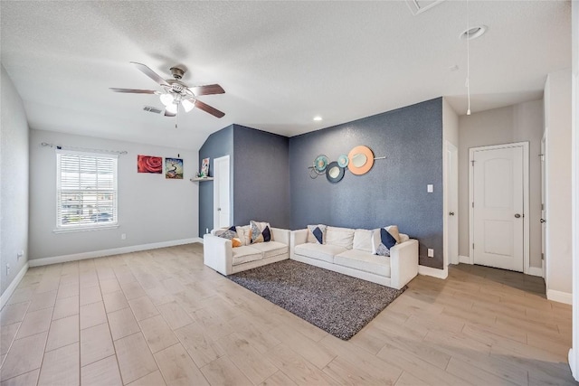 living room with attic access, light wood-type flooring, a ceiling fan, and baseboards