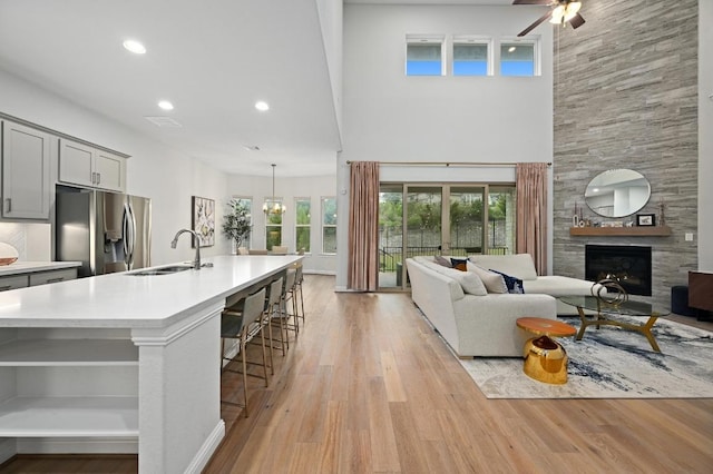 233 Abbeyville Walk, Austin, TX 78738 - living area featuring light wood-style flooring, a tiled fireplace, a ceiling fan, recessed lighting, and a towering ceiling
