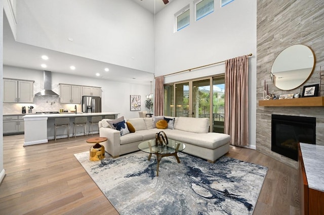 233 Abbeyville Walk, Austin, TX 78738 - living room featuring a large fireplace, a ceiling fan, light wood-style flooring, a towering ceiling, and recessed lighting