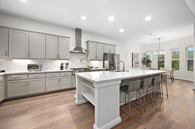 233 Abbeyville Walk, Austin, TX 78738 - kitchen featuring wall chimney exhaust hood, gray cabinetry, appliances with stainless steel finishes, decorative backsplash, and a sink