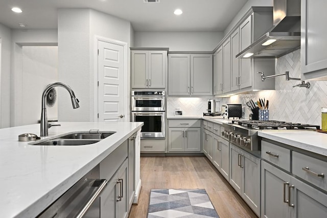233 Abbeyville Walk, Austin, TX 78738 - kitchen featuring gray cabinetry, wall chimney exhaust hood, stainless steel appliances, a sink, and recessed lighting