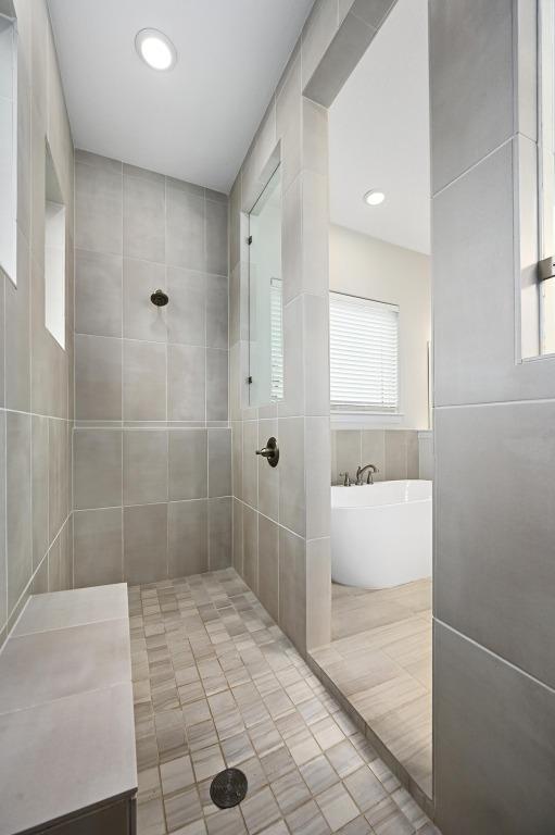 233 Abbeyville Walk, Austin, TX 78738 - full bathroom with tile patterned flooring, plenty of natural light, a soaking tub, tiled shower, and tile walls