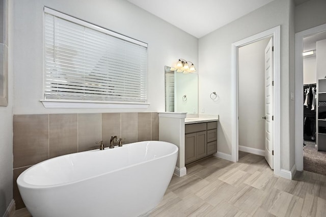 233 Abbeyville Walk, Austin, TX 78738 - bathroom with a soaking tub, vanity, a spacious closet, and baseboards