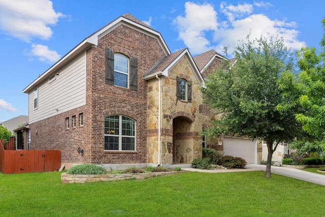 traditional home with driveway, a front yard, brick siding, and stone siding
