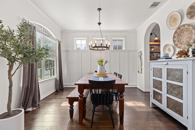 dining space featuring crown molding, a notable chandelier, visible vents, and dark wood finished floors