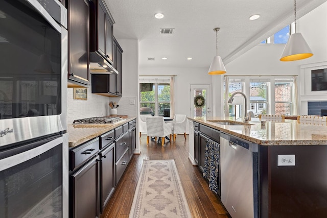 kitchen featuring light stone counters, a sink, visible vents, stainless steel appliances, and dark wood-type flooring