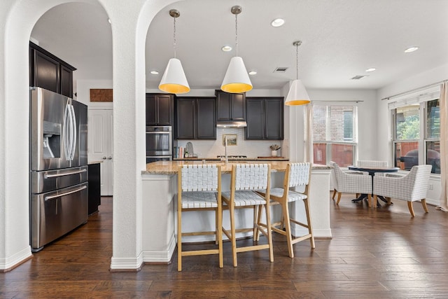 kitchen featuring light stone counters, stainless steel appliances, recessed lighting, and arched walkways