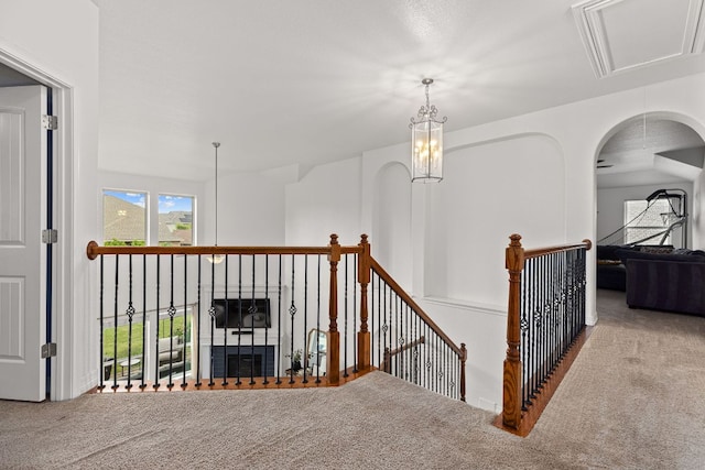 hallway with an upstairs landing, attic access, and carpet flooring
