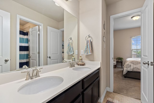 ensuite bathroom with connected bathroom, tile patterned flooring, double vanity, and a sink