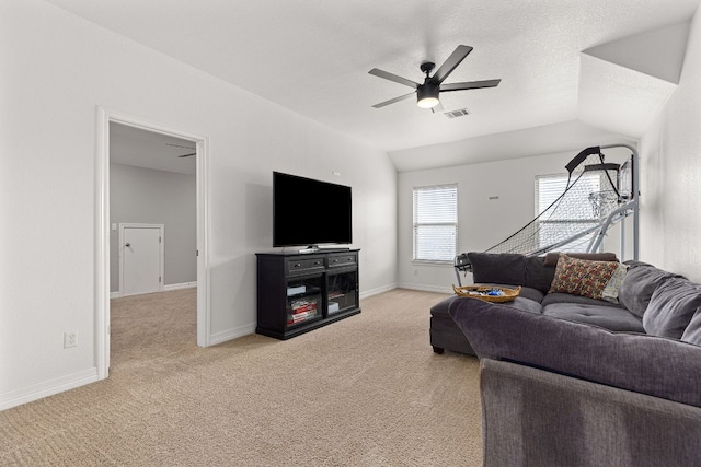living room with lofted ceiling, light colored carpet, visible vents, baseboards, and a ceiling fan