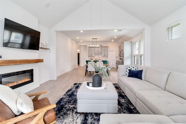 1109 Sweetspire St, Leander, TX 78641 - living room with lofted ceiling, a chandelier, light wood-style floors, a glass covered fireplace, and recessed lighting