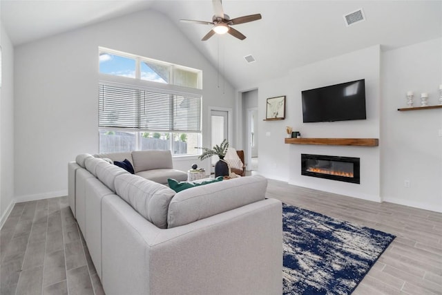 1109 Sweetspire St, Leander, TX 78641 - living room with wood finished floors, ceiling fan, a glass covered fireplace, high vaulted ceiling, and baseboards