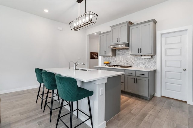 1109 Sweetspire St, Leander, TX 78641 - kitchen with gray cabinets, under cabinet range hood, gas stovetop, a kitchen island with sink, and recessed lighting