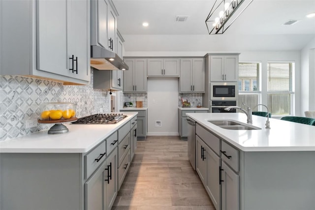 1109 Sweetspire St, Leander, TX 78641 - kitchen with gray cabinets, under cabinet range hood, a sink, appliances with stainless steel finishes, and recessed lighting