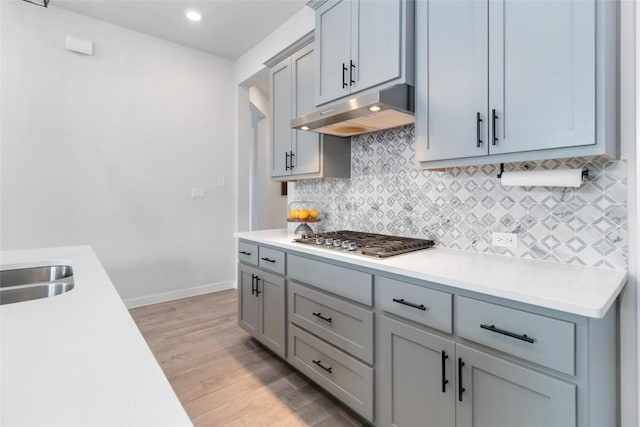 1109 Sweetspire St, Leander, TX 78641 - kitchen featuring under cabinet range hood, stainless steel gas cooktop, light countertops, backsplash, and light wood finished floors