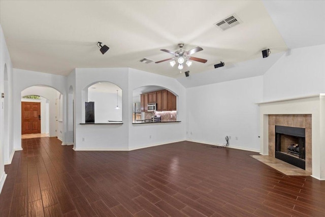 unfurnished living room with dark wood-style floors, visible vents, a ceiling fan, and a tile fireplace