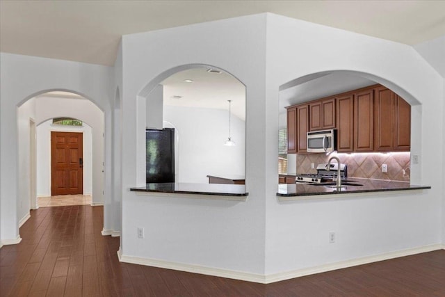 kitchen featuring tasteful backsplash, dark countertops, stainless steel appliances, and dark wood-type flooring