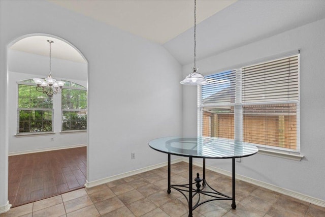 unfurnished dining area featuring an inviting chandelier, plenty of natural light, lofted ceiling, and baseboards