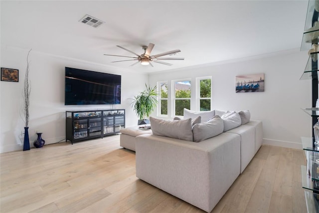 living room with visible vents, ornamental molding, light wood finished floors, and ceiling fan